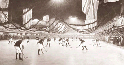 Sechs Männer in Wollpullovern und Schiebermützen spielen um 1900 mit Holzschlägern Eishockey auf einem zugefrorenen Weiher in Kanada, im Hintergrund ein Blockhaus