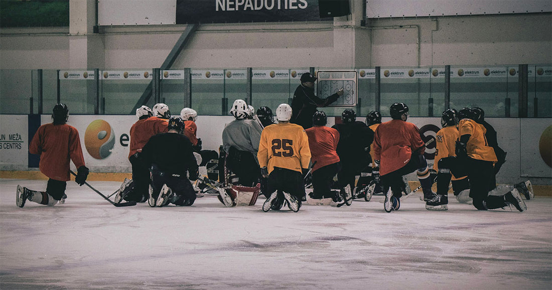 Eishockeymannschaft im Training: Spieler hören aufmerksam ihrem Coach zu, um wertvolle Tipps zur Verbesserung ihrer Fähigkeiten zu erhalten.